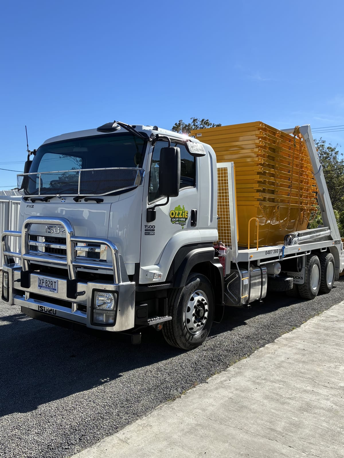 Ozzie Skip Hire Isuzu skip-bin delivery truck carrying yellow skip bins on the Coffs Coast.